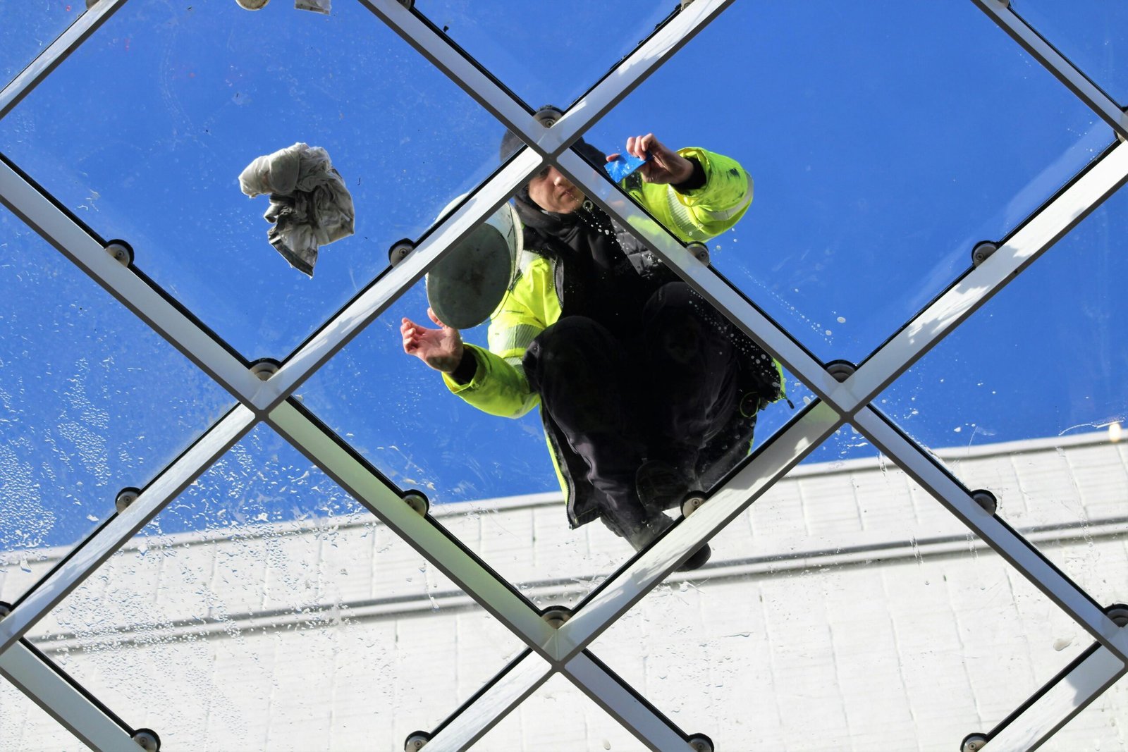 Man cleaning glass roof in Tilburg, Netherlands, showcasing architectural and labor perspective.